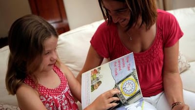 Annabelle White uses an Aramazu children’s book to teach her daughter Juliette, 6, how to read a clock.