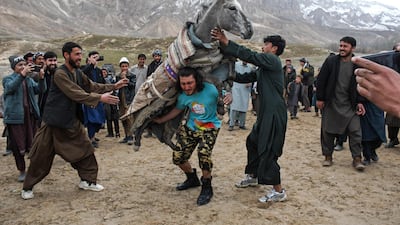 Afghan athlete Mudasir Tahiri, centre, carries a donkey on his shoulder to show his strength in the Nahr Shahi district of Balkh province. AFP