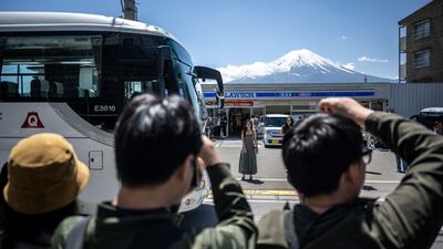 Tourists photograph Mount Fuji from a vantage point opposite a convenience store in the Japanese resort town of Fujikawaguchiko. AFP