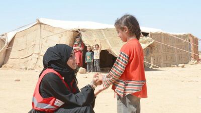 A member of the UAE Red Cresent talking to a Syrian child refugee. The UAE pledged another US$60m to refugees in Syria on April 1, 2014. Wam