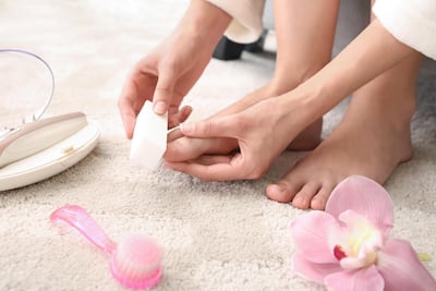 TBH7BX Young woman polishing her nails at home. Alamy