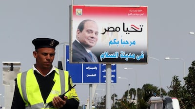 An Egyptian traffic soldier stands near a poster depicting Egyptian president Abdel Fattah El Sisi and Arabic reading 'welcome to the peace city', one day before the Economic Development Conference (EEDC), in the Red Sea resort of Sharm El-Sheikh. Khaled Elfiqi / EPA