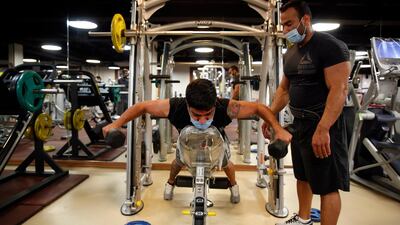 Iranian bodybuilder Siyavosh Mafi wearing face mask coaches his athlete workout in a gym in Tehran. EPA