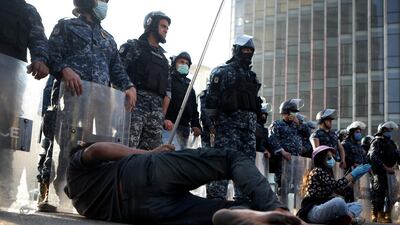 A barefoot Lebanese protester lies on the tarmac in front of riot police in the capital Beirut. AFP