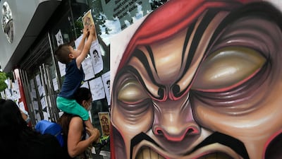 The son of a Nissan employee sticks a paper on the window of an authorised dealer of the Japanese cars manufacturer next to a placard depicting a Japanese traditional Daruma doll in Barcelona, Spain. AFP