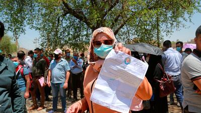 Rowaida Abdul Rahman shows her science master's degree certificate while jobless graduates gather in front of the Ministry of Oil to demand jobs in Baghdad, Iraq. AP