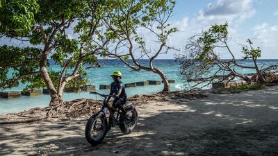 A boy rides his bike along the shoreline in Mahibadhoo, Maldives. Getty