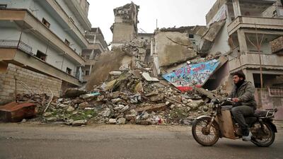 A Syrian man rides his motorcycle past a damaged building following an air strike by pro-regime forces on the rebel-held town of Ariha in the northern countryside of Syria's Idlib province. AFP