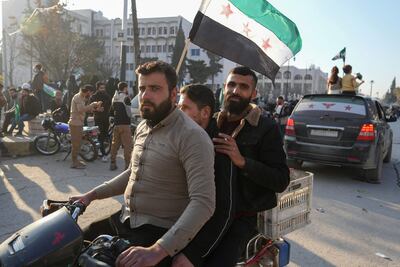 People wave pre-Assad era Syrian flags on a street in Idlib to celebrate the overthrow of Bashar Al Assad. AFP