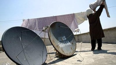 An Iranian woman, standing next to two satellite dishes. News Corporation plans to launch two Farsi-language TV stations through its Dubai-based joint venture with a local media firm. AFP PHOTO/Behrouz MEHRI
