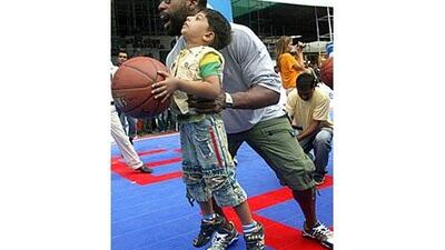Baron Davis, of the Los Angeles Clippers, helps an Indian boy during a basketball awareness event in Mumbai in July 2009.