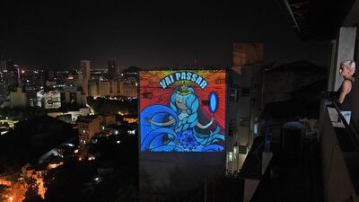 This picture taken on March 23, 2020 shows graffiti artist Rafamon projecting her artwork with a message that reads, "Vai Passar" (It will pass) onto a building near her home in Rio de Janeiro, after she decided to self-isolate as a preventive measure against the COVID-19 novel coronavirus. - RESTRICTED TO EDITORIAL USE - MANDATORY MENTION OF THE ARTIST UPON PUBLICATION - TO ILLUSTRATE THE EVENT AS SPECIFIED IN THE CAPTION / AFP / Carl DE SOUZA / RESTRICTED TO EDITORIAL USE - MANDATORY MENTION OF THE ARTIST UPON PUBLICATION - TO ILLUSTRATE THE EVENT AS SPECIFIED IN THE CAPTION
