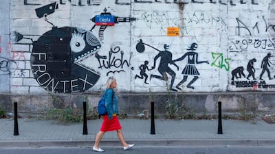 A woman passes by a Frontex- critical mural near the headquarter of the European Union border force Frontex in Warsaw, Poland, on August 5, 2019. The European Union border force Frontex has allegedly been turning a blind eye to ill treatment of refugees by guards at EU external borders, according to media reports. AFP