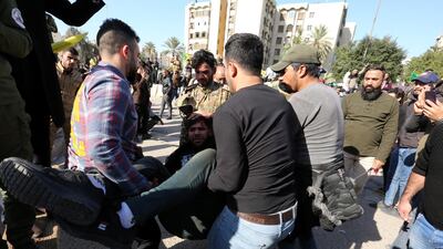 Members of Iraqi Popular Mobilisation Forces and their supporters help their comrade who was wounded during their attempt to attack the US embassy in Baghdad. EPA