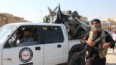 An ISIL militant walks past a pick-up truck loaded with the wreckage of a Syrian air force plane that was shot down by militants over the Syrian town of Raqqa on Tuesday. AFP