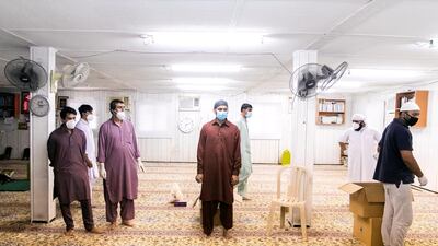 Volunteers at the iftar distribution in Dubai Investment Park, inside a small mosque, pick up their iftars. Reem Mohammed/The National