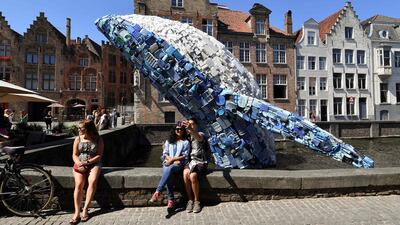 Tourists pose for a selfie picture with a 12-metre installation depicting a whale, made up of five tons of plastic waste pulled out of the Pacific Ocean, displayed in Brugges, on July 14, 2018 for the 2018 Bruges Triennial. John Thys / AFP