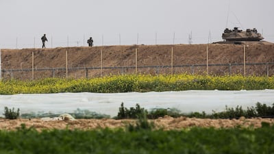 Israeli soldiers walk behind a tank along the Israel-Gaza border east of Khan Yunis in the southern Gaza Strip. AFP