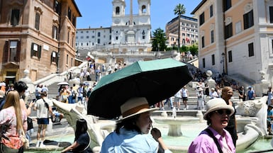 Tourists shield themselves from the sun with hats and umbrellas at the Spanish Steps in Rome, with much of Europe in the grip of an early-season heatwave. AFP