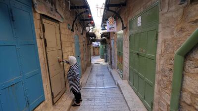A woman opens her door in the closed main tourist market in the northern city of Nazareth. Israel unveiled its plan to restore inbound tourism in an effort to bring the economy back to normal amid the coronavirus pandemic. AFP