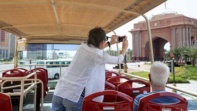 A tourist takes a picture of Emirates Palace on The Big Bus Tour. Mona Al Marzooqi / The National