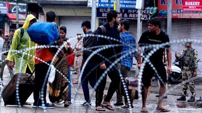 People walk past barbed wire placed on a street in Jammu on August 5, 2019. AFP