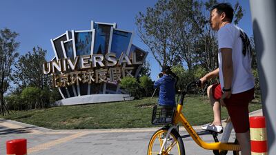 A man uses a bike-sharing service near a giant sign for Universal Beijing Resort, ahead of its opening. Reuters