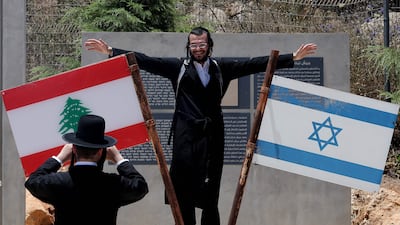 Jewish men poses beside Israeli and Lebanese flags at a memorial site on the border with Lebanon in northern Israel. AFP