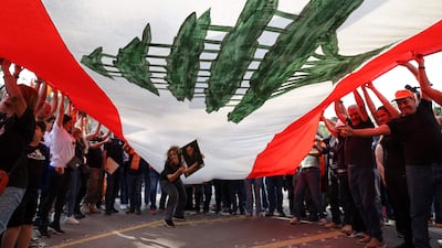 Supporters of Lebanon's President Michel Aoun cheer under a large national flag, as he prepares to leave the presidential palace in Babbda at the end of his mandate. AFP