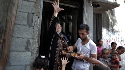 A woman throws candy at friends of Saed Abu Aser, as they pass through the neighborhood dancing, before his wedding party.