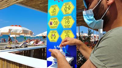 A man wearing a protective face mask sanitises his hands on a beach that was reopened last week after months of closure due to an outbreak of the coronavirus, in Castiglione della Pescaia, Italy on May 31, 2020 Reuters