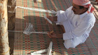 A man weaves fishing nets at the Al Gharbia Watersports Festival.