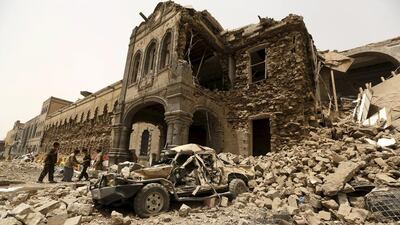 Houthi militants stand in front of the defence ministry compound after it was hit by Saudi-led airstrikes in Yemen's capital Sanaa . Khaled Abdullah/Reuters