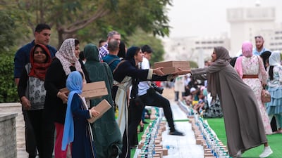 Jusoor volunteers distribute iftar meals at the mosque. Victor Besa / The National