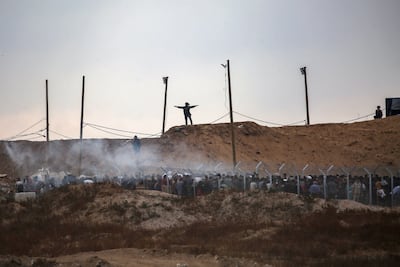 Members of a private US security company, contracted by the GHF, direct Palestinians at an aid point in central Gaza, as smoke bombs are fired by Israeli troops. AFP