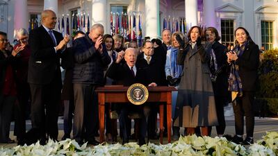 Mr Biden raises his pen after signing the bill. AP