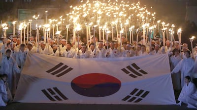 South Koreans hold up lit torches with the national flag. AFP
