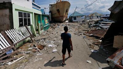 A man walks past a ferry boat that was swept ashore near Palu when a magnitude 7.5 quake and tsunami hit Indonesia's Central Sulawesi province September 28, 2018. Dita Alangkara / AP Photo
