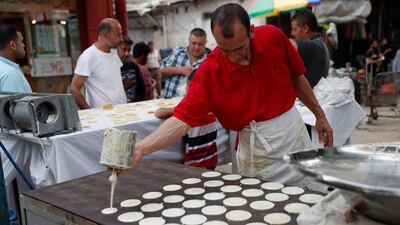 A vendor prepares sweets, qatayef, a pancake-like shell which is filled with nuts or sweet cheese, fried in oil or baked then dipped in sugar syrup, a popular sweet during Ramadan at the main market of Shijaiyah neighbourhood in Gaza City. AP Photo