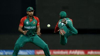 Bangladesh fielder Mohammed Mithun, right, dives to take a catch as team captain Masarfe Bin Mortaza watches during the World T20 tournament match between Australia and Bangladesh at The Chinnaswamy Stadium in Bangalore on March 21, 2016. MANJUNATH KIRAN / AFP