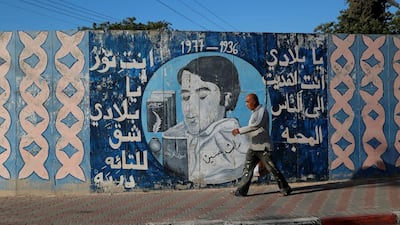 A man walks past a mural with writing in Arabic that reads, "My country, you gave us love and light, which revealed paths for the lost" in the Israeli Arab city of Umm Al Fahm. Ammar Awad / Reuters