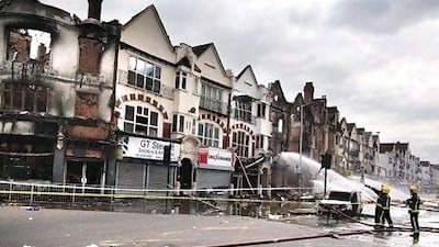 Firemen damp down smouldering buildings in Croydon.The back of the complex housing the UAE Exchange was completely gutted.