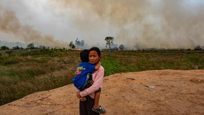 Poppy, 12, and her brother look on as Indonesian firefighters try to extinguish a peatland fire near her house in Palembang, South Sumatra. AFP
