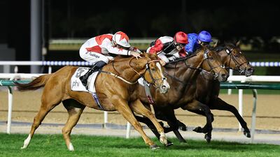 Patrick Dobbs, centre, rides Poker Face to victory at the Meydan Racecourse in Dubai. Pawan Singh / The National