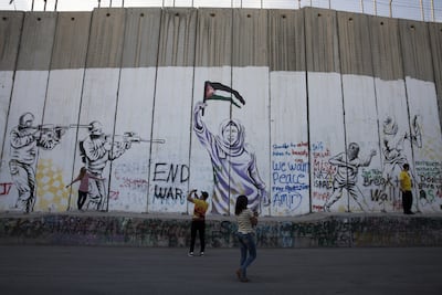 Tourists visit the concrete separation wall in the Palestinian city of Bethlehem. The separation barrier has become a tourist attraction, drawing visitors from all over the world. Heidi Levine / The National