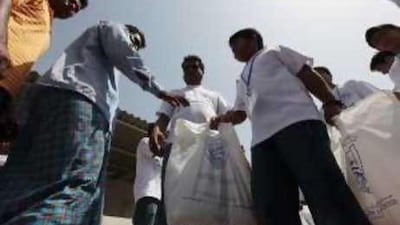 Labourers receive parcels of rice and lentils from the Our Own High School pupils at a camp in Sonapur, Muhaizna, Dubai.