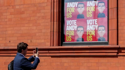 A man takes photos of campaign placards that read "Vote Andy For Us", displayed in the windows of Cross Keys pub, in Ashton-in-Makerfield, Britain. Reuters