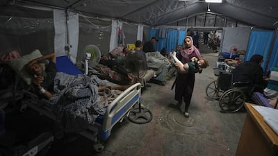 A mother carries her child into a patient treatment tent set up in the yard of the hospital