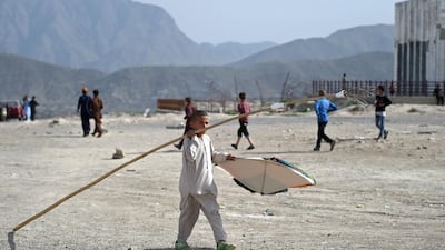 A boy carries a stick on his shoulder during a kite battle.