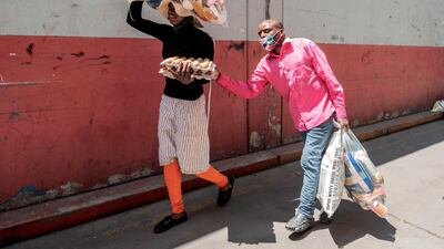 A woman walks with her blind husband as they carry a food parcel collected during a food distribution leaded by the international NGO Gift to the Givers, in Johannesburg CBD, on October 14. Luca Sola / AFP